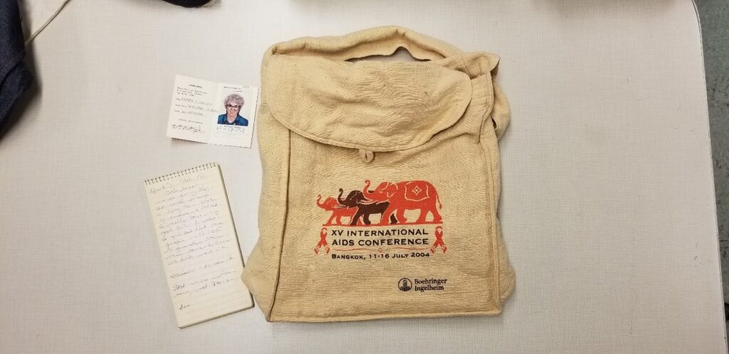 A conference bag with several flyers for HIV/AIDS conferences laying on a table. 