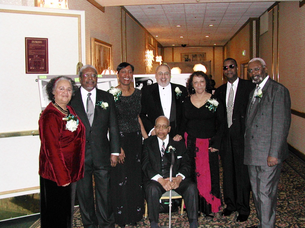 Group photograph of the original Members at the UCSF Black Caucus Gala in February 2005. From left to right are Elba Clemente-Lambert, Charles Clarey, Claudette Coleman, Freeman Bradley, Anitra (Koehler) Patterson, Paul Porter, Leon Johnson, and Walter "Pop" Nelson (sitting).